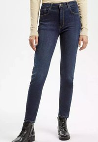 Ciemnoniebieskie jeansy z wysokim stanem i slim fit, z pi ęcioma kieszeniami, subtelnymi szwami oraz klasycznym zapięciem na guzik z przodu.