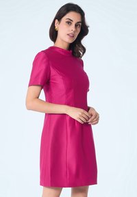 Robe fuchsia à manches courtes avec un col haut et une silhouette ajustée. Fabriquée en tissu lisse et brillant avec des coutures discrètes.