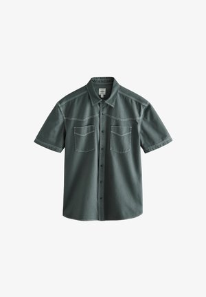 Short-sleeve shirt in dark green, made of textured fabric. Features two front pockets and visible stitching along the seams and collar.
