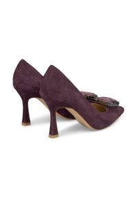 Chaussures à talons hauts en daim violet avec un bout pointu et un accent décoratif à l'avant. Le talon est mince et effilé, mettant en valeur le design.