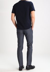 Mörk marinblå t-shirt med korta ärmar och rundad nederkant, tillsammans med smalpassande grå byxor och svarta anklarstövlar.