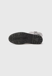 Juodas bato padas su širdelės formos raštais ir "LOVE MOSCHINO" įspaustu centre, matomas iš apačios ant pilko fono.