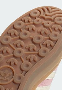 Gumená podrážka s textúrovaným vzorom z kruhových a listových tvarov. Farby zahŕňajú svetlohnedé a svetloružové akcenty.