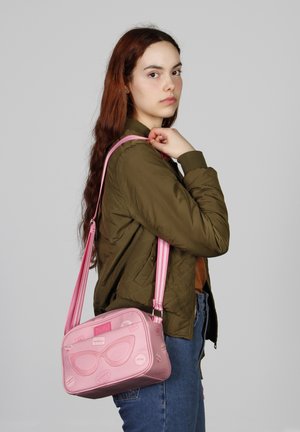 Sac bandoulière rose avec un graphique de lunettes de soleil, des accents gaufrés et une bandoulière rayée. Matériau doux, forme rectangulaire, design décontracté.