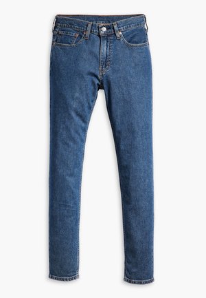 Niebieskie dżinsy o slim fit, pięciu kieszeniach i surowym wykończeniu na kostkach. Posiadają mosiężne okucia i pomarańczowe akcenty szycia.