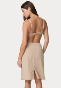 Beżowa sukienka na ramiączkach z rozporkiem z tyłu i koronkowym wykończeniem; wykonana z gładkiego materiału. Regulowane ramiączka łączą się z zapięciem na haczyk.