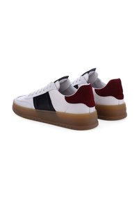 Witte leren sneakers met zwarte en bordeauxrode accenten, ronde neus, gevoerde kraag en een doorschijnende rubberen zool. Kenmerkt zich door een slank ontwerp.
