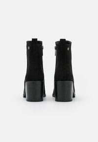Botines negros de ante suave, con puntera redonda, tacón bloque de altura media y cremalleras laterales para un fácil uso.