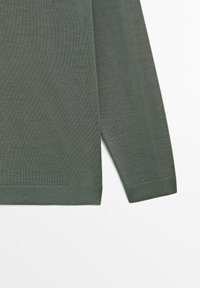 Green long-sleeve shirt made of textured fabric, featuring ribbed cuffs and hem, with a straight cut and no visible patterns or accents.