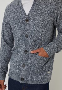 Cardigan a maglia in blu scuro e grigio, con scollo a V, sei bottoni, polsini a coste e due tasche laterali. Tessuto texture con una finitura morbida.