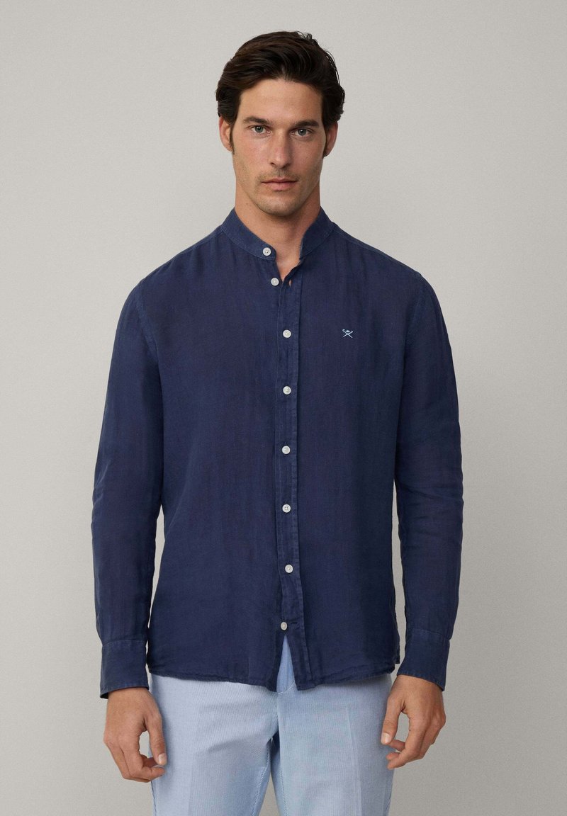 Camicia a maniche lunghe blu navy con colletto a costina, bottoni bianchi e tessuto leggermente testurizzato. Presenta un piccolo logo ricamato sul petto.