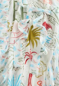 Biela látka s viacfarebnými ilustráciami námorných motívov, abstraktnými tvarmi a roztrúseným ručne písaným textom v rôznych farbách.