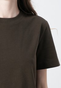Brown cotton T-shirt with a crew neckline and short sleeves. The fabric is smooth with a plain design and a relaxed fit.