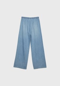 Ljusblå denim byxor med vida ben och elastisk midja, som har en mjuk textur och en avslappnad passform. Inga fickor eller ytterligare detaljer.