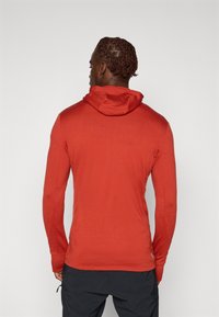 Rode hoodie met lange mouwen en een relaxte pasvorm, voorzien van een trekkoordhoed, rib gebreide manchetten en een soepele textuur. Achteraanzicht zonder grafische elementen of logo's.