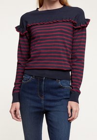 Svetri tamsiai mėlynai ir burgundiškai dryžuotas, su volanų akcentais ir vientiso audinio apykakle, pagamintas iš megztos medžiagos su prigludusia juosmeniu.