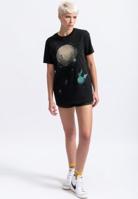 Zwarte katoenen t-shirt met een grafisch ontwerp van planeten en sterren in teal, met korte mouwen en een losse pasvorm.