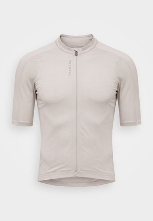 Maillot de ciclismo de manga corta de color beige claro con cremallera frontal completa y pequeño logo vertical en el pecho izquierdo.