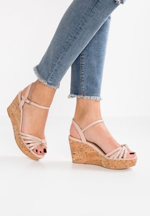 Beige wedge sandals with cork platform and strap design. Open-toe style with crisscrossed straps and ankle buckle detail.