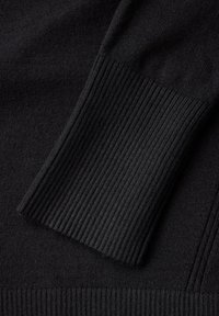 Black knitted sweater detail featuring ribbed cuffs and hem, smooth texture, and a consistent color throughout the fabric.
