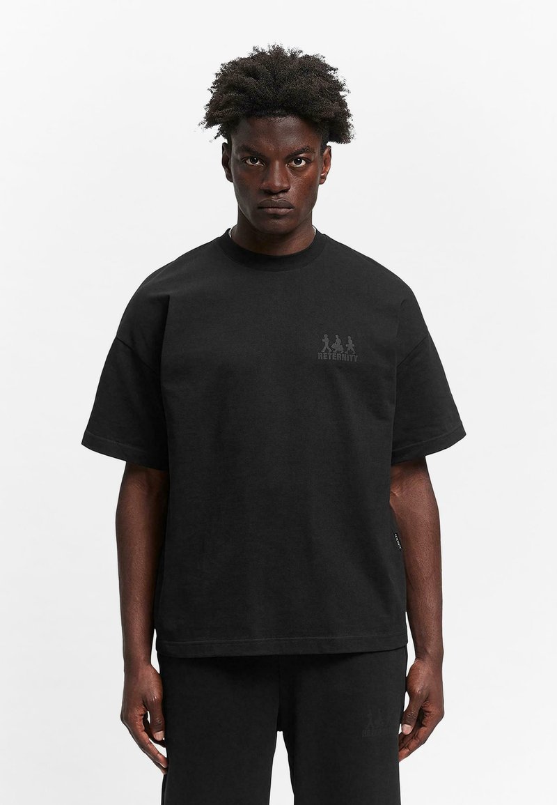 Black cotton t-shirt with short sleeves, relaxed fit, embroidered logo on the chest, and a smooth texture. Paired with black pants.