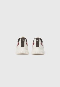 White athletic shoes with maroon and black accents. Soft textured upper, contrasting rear pull tab, and a thick cushioned sole.