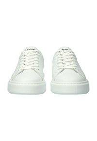 Pari valkoisia matalavartisia tennareita, joissa valkoiset nauhat ja paksut pohjat, kielen kohdalla ”Blackstone”-merkki, kuvattu edestä.