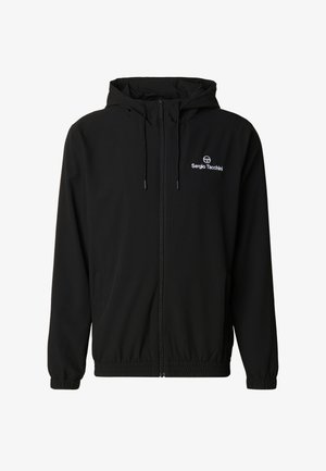 Svart hettejakke laget av lett stoff, med glidelås foran, elastiske mansjetter og en liten brodert logo på brystet.