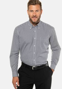 Zwart-wit geblokt overhemd met een button-down kraag, lange mouwen en een slim-fit ontwerp; gedragen met een zwarte riem en broek.