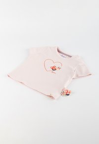 Pink cotton short-sleeve shirt featuring an embroidered ladybug inside a heart design. Includes a decorative tag with a ladybug illustration.
