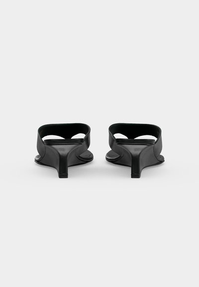 Paire de sandales mules noires à talon bas vues de dos sur fond blanc uni.