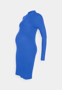 Ribbad, långärmad gravidklänning i klart blått. Har hög krage och tight passform, utformad för att rymma en växande mage.