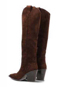 Botas marrones de ante hasta la rodilla con punta afilada y tacón inclinado. Detalles de costura notables y una tira en la parte superior para facilitar el uso.