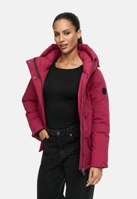 Magenta pufferjack met een afneembare capuchon, zijzakken en ritssluiting. Draag het over een zwarte top en gecombineerd met zwarte jeans.