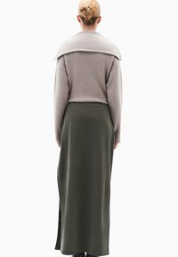 Grå sweater med en foldet krave, parret med en lang olivengrøn nederdel med en sideslids. Glat tekstur, afslappet pasform og minimale syninger.