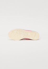 Mehrfarbige Sneaker-Sohle mit einer strukturierten Gumm Oberfläche, die pinke, graue und cremige Segmente sowie geometrische Musterdetails aufweist.