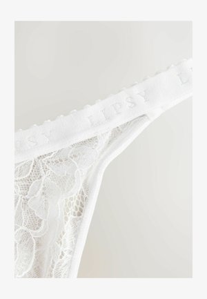String en dentelle blanche avec un design texturé et des motifs floraux. La taille est ornée d'un doux logo brodé "Lipsy".