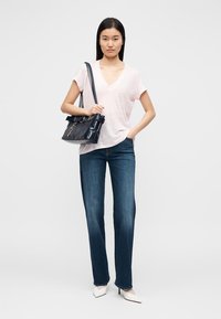 Ροζ ανοιχτό ροζ T-shirt με λαιμόκοψη σε σχήμα V, σκούρο μπλε τζιν με ίσια γραμμή, λευκές γόβες με μυτερή μύτη και σκοτεινή τσάντα με δομημένο σχέδιο.