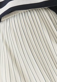 Gonna a pieghe in tessuto leggero, con righe verticali blu navy su sfondo crema. Vita elastica per il massimo comfort.