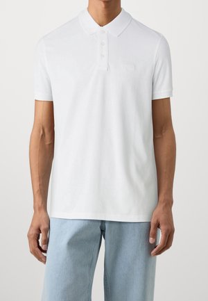 Wit poloshirt van zacht katoen, met een klassieke kraag, een knoopsluiting met drie knopen, korte mouwen en een subtiel reliëflogo op de borst.