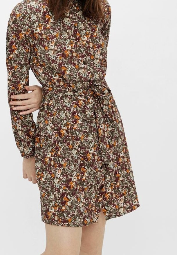 Robe fleurie avec un motif multicolore sur un fond vert foncé, à manches longues, taille cintrée par un lien et ouverture à boutons.
