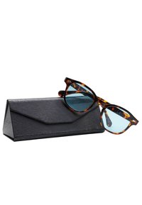 Occhiali da sole tartarugati con lenti bluastre, appoggiati parzialmente su una custodia triangolare nera testurizzata.