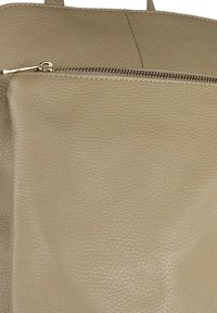 Beige leren tote bag met een textuurafwerking, voorzien van een ritssluiting aan de bovenkant en een stijlvol ontwerp. Geen zichtbare merkmerken of versieringen.