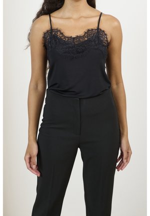 Camisole nera con scollatura in pizzo e sottili spalline, abbinata a pantaloni neri a vita alta. Texture liscia in tutto.