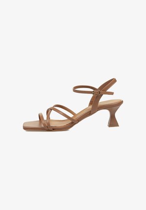 Sandalias marrones de tiras con puntera cuadrada y un tacón angulado único. Fabricadas con material suave, cuentan con delicadas correas ajustables.
