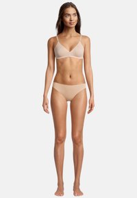 Reggiseno wireless beige con spalline regolabili e slip senza cuciture coordinati, entrambi realizzati in tessuto morbido e elastico, con un design semplice.