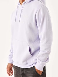 Sudadera de color púrpura claro hecha de tela suave, con un bolsillo frontal, cordones y un logo de corazón bordado en el pecho.