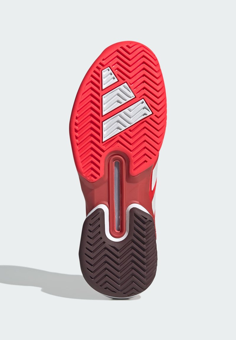 Semelle de chaussure de sport rouge avec un motif en chevrons texturé, présentant des accents blancs et un élément de coussin d'air visible.