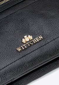 Černá kožená peněženka s texturovaným povrchem a zlatě embosovaným logem se znakem. Zipperové zapínání na vrchu.