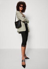 Grå ternet blazer, sort top, leggings med blondekant, sort håndtaske og spidse hæle med guld accenter. Solbriller fuldender looket.